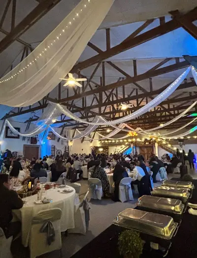 The barn set for a reception with long tables and string lights overhead