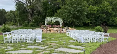 Rows of white ceremony chairs along the garden stone pathway