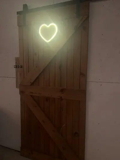 A glowing heart light above the barn doors in the evening