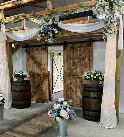 The draped barn entrance with barrels and floral arrangements