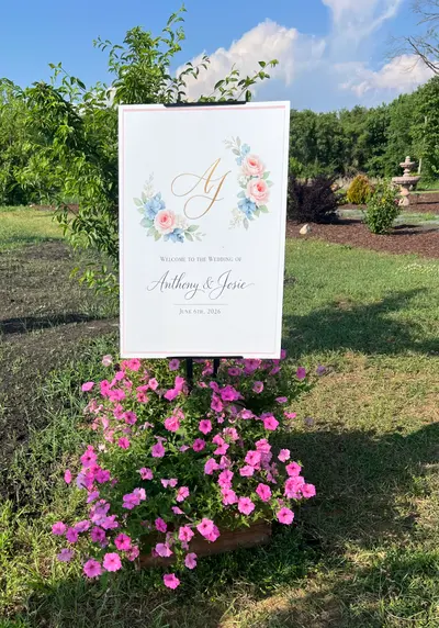 A framed wedding sign beside fresh pink flowers