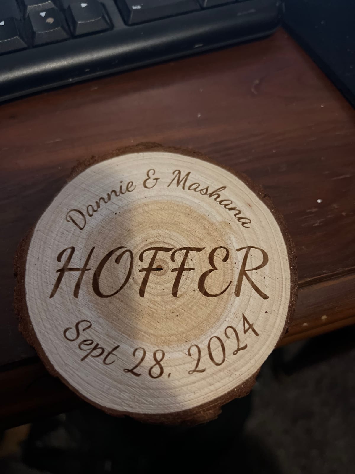 A natural wood tree-slice disk engraved with the Hoffer family name, the couple’s first names, and their wedding date